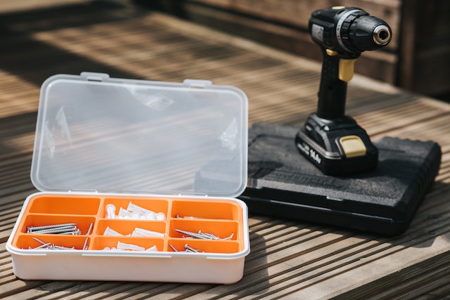 orange tool box with nails and screws and a drill